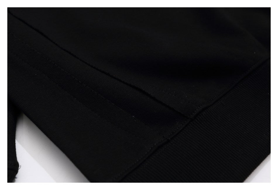 Close-up of stitching and ribbed hem on a black sweatshirt.