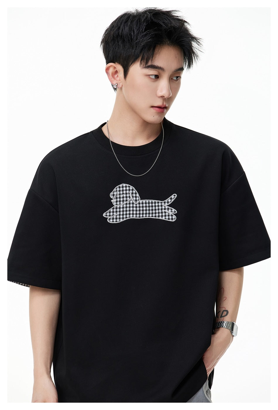 Close-up of model wearing black T-shirt with gingham dog appliqué and dropped shoulders