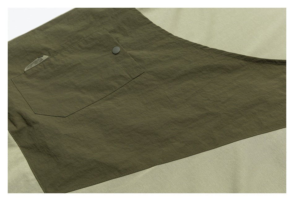 Close-up of an olive-green garment pocket with a snap button and a small fabric tab.