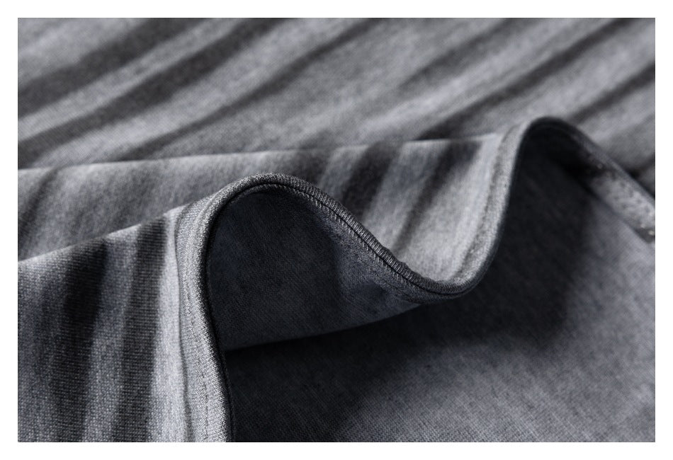 Close-up of gray-and-charcoal striped fabric folded to show its dark underside and finished edge.