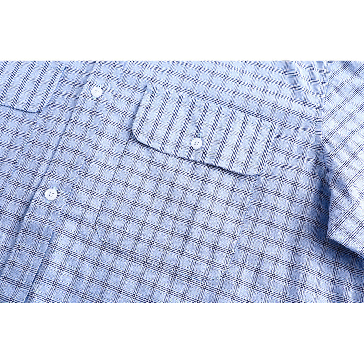 Close-up of a light blue plaid shirt front with a buttoned flap chest pocket and white buttons.