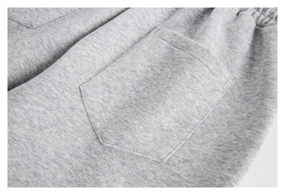 Close-up of a stitched patch pocket on the back of light gray heather sweatpants.