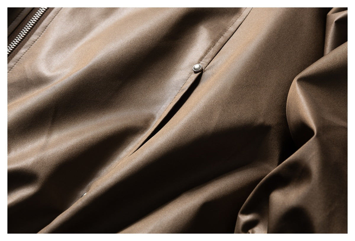 Close-up of a snap-button pocket flap and smooth brown jacket fabric.