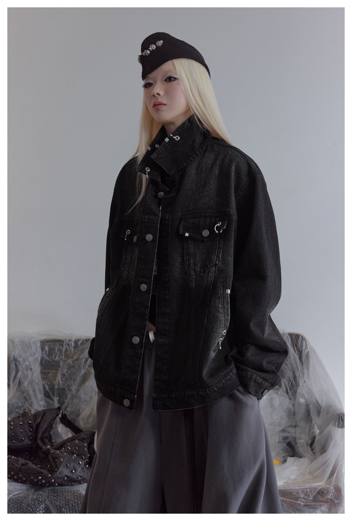 Model wearing an oversized black denim jacket with a high collar and silver hardware.