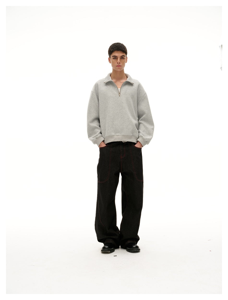 Model in a gray half-zip sweatshirt with hands in the pockets of wide dark jeans, full-length view
