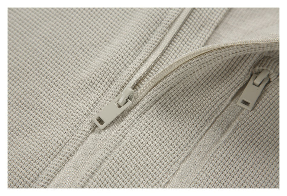 Close-up of the pullover's front zipper pulls, zipper tape, and textured fabric.