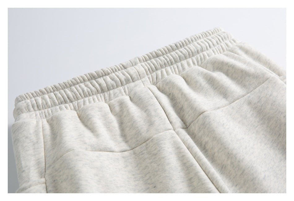 Close-up of light gray heathered sweatpants showing the elastic waistband and pocket stitching.