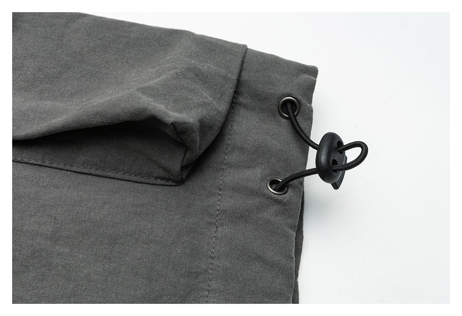 Close-up of charcoal gray garment fabric with a black elastic cord and toggle fastener.