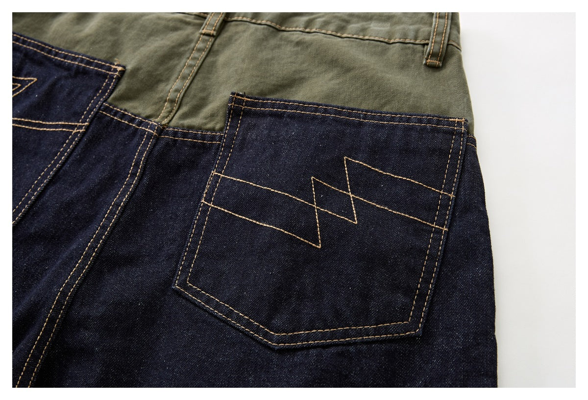 Close-up of a dark denim back pocket with angular tan stitching beneath an olive waistband.