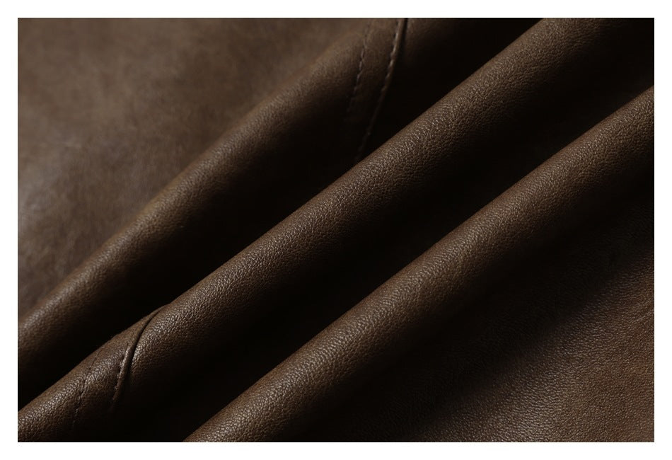 Close-up of a brown pebbled garment surface arranged in folds, with a curved stitched seam.