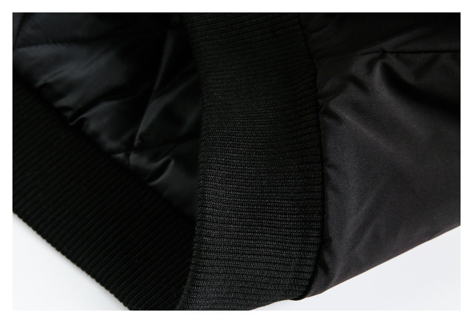 Close-up of a black jacket's ribbed hem and smooth outer fabric.