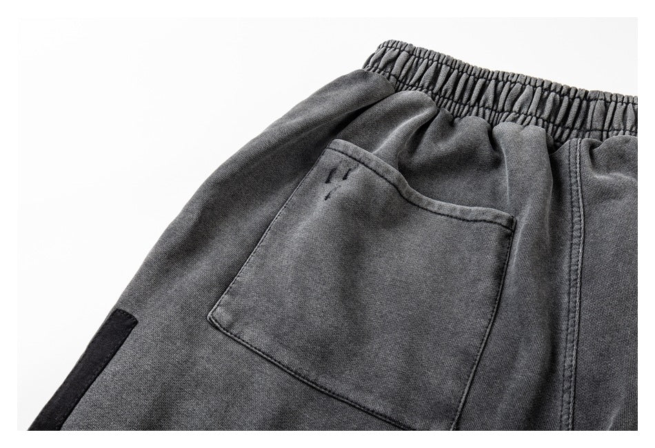Close-up of charcoal gray joggers showing an elastic waistband and a stitched rear pocket.