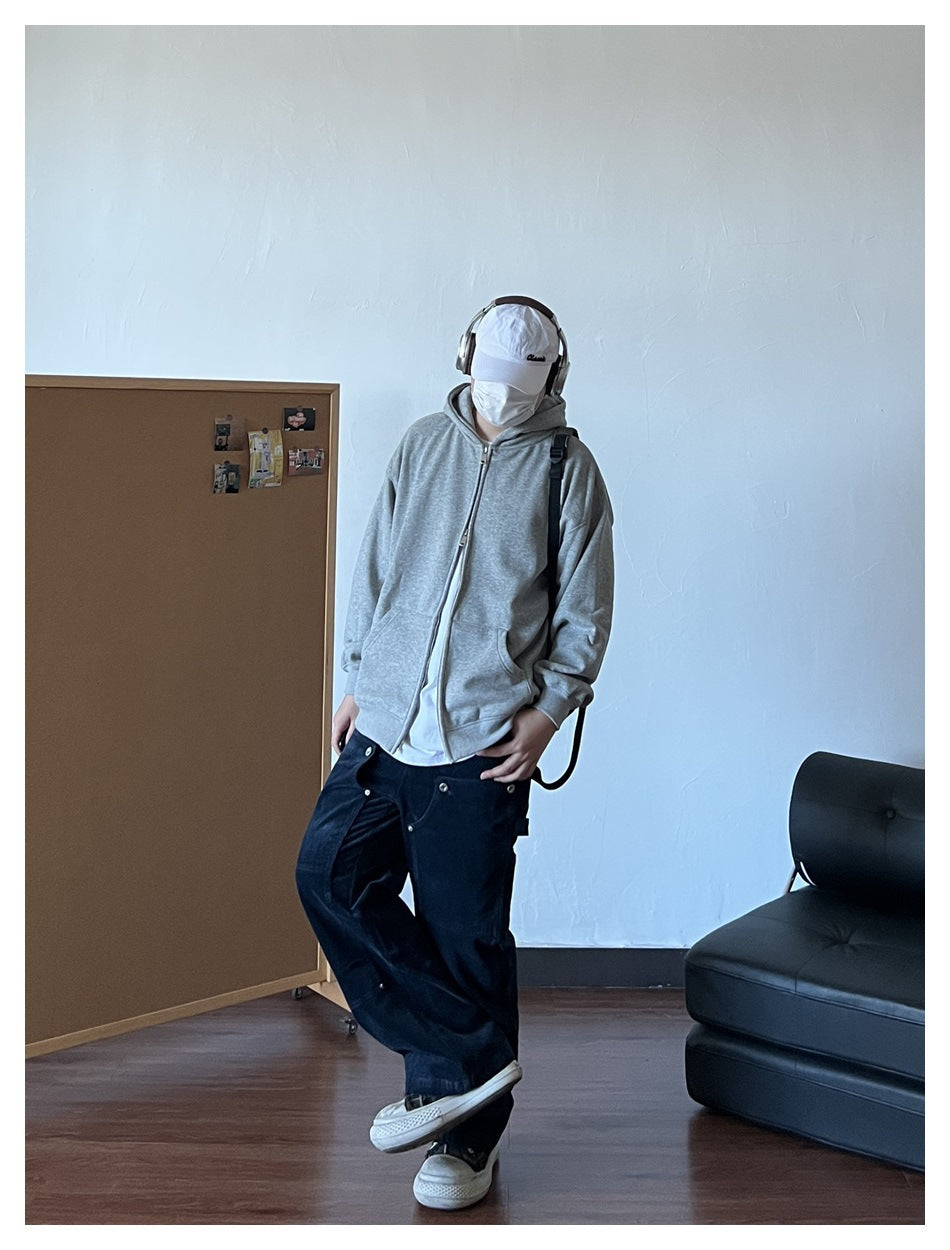 Person wearing a heather-gray zip-up hoodie with the hood down, paired with dark jeans.