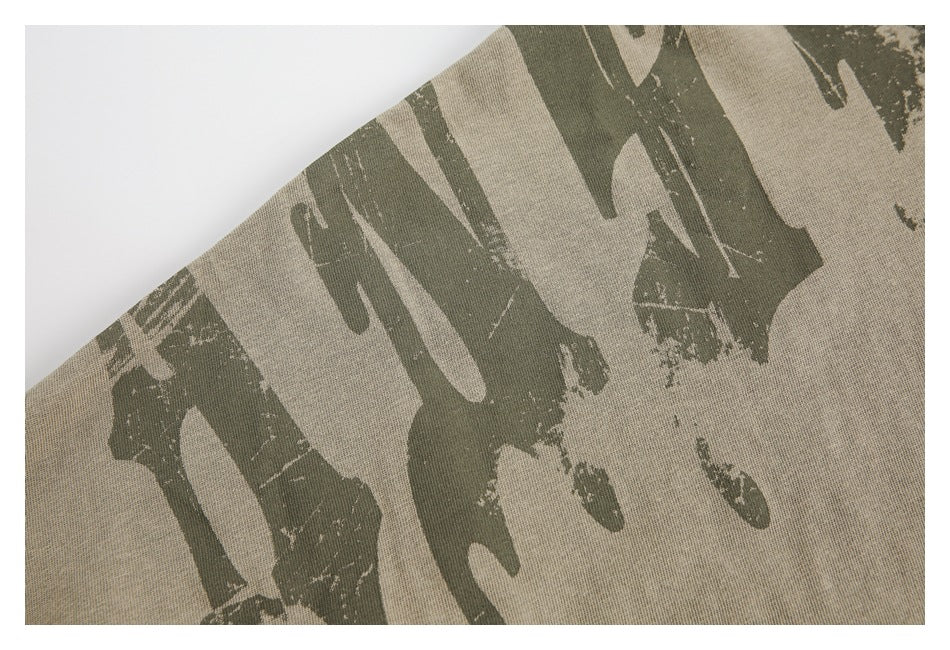 Close-up of a distressed dark olive graphic print on tan fabric.