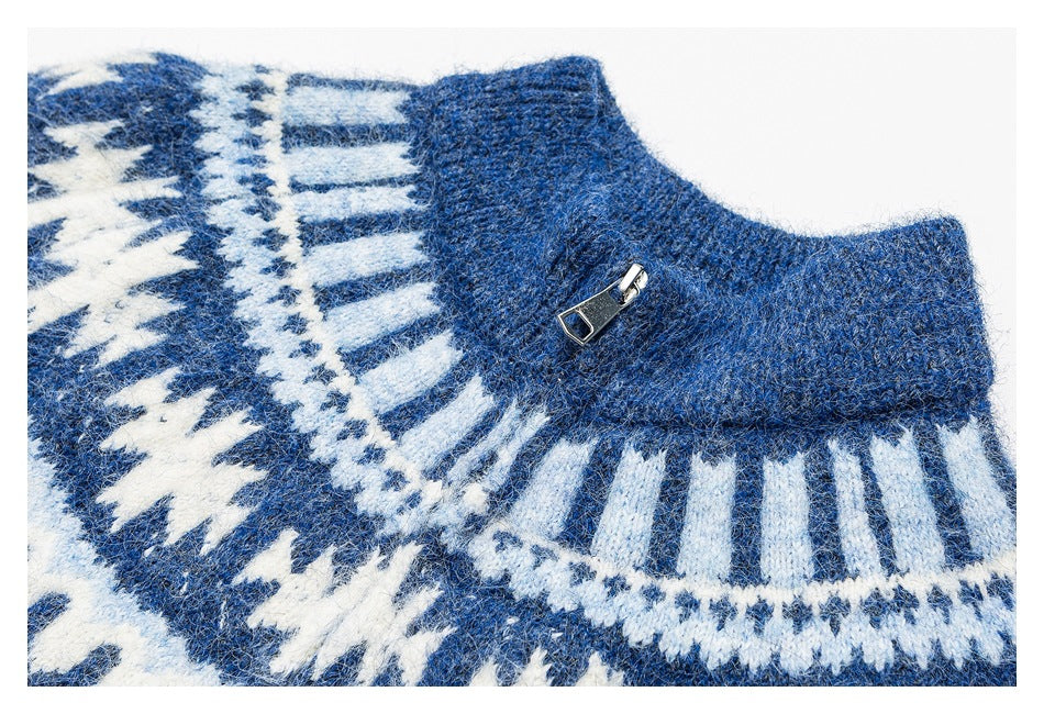 Close-up of a blue sweater's white geometric yoke pattern and ribbed collar with a small metal zipper pull.