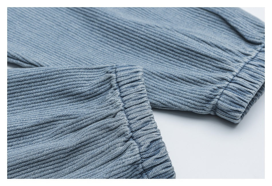 Close-up of blue-gray ribbed garment fabric with gathered elastic cuffs.