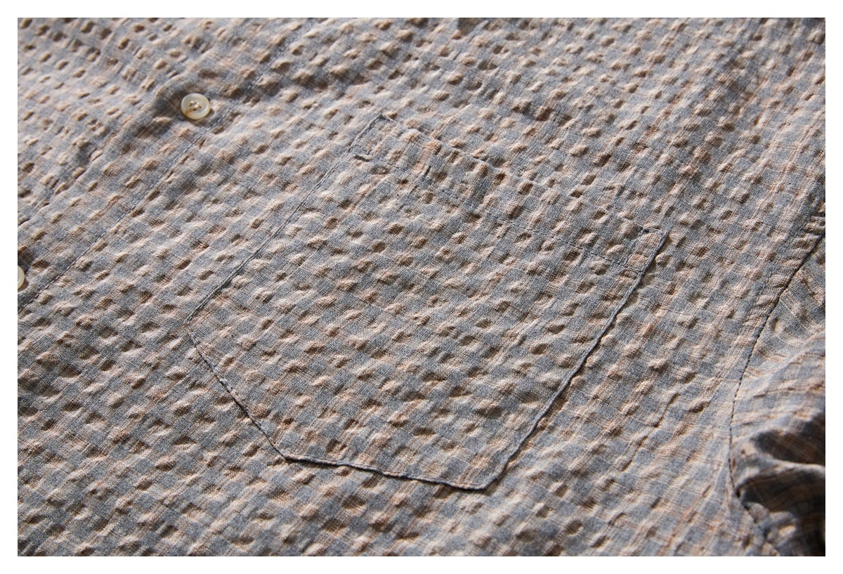 Close-up of a gray-brown patterned shirt showing a large patch pocket and a light button.