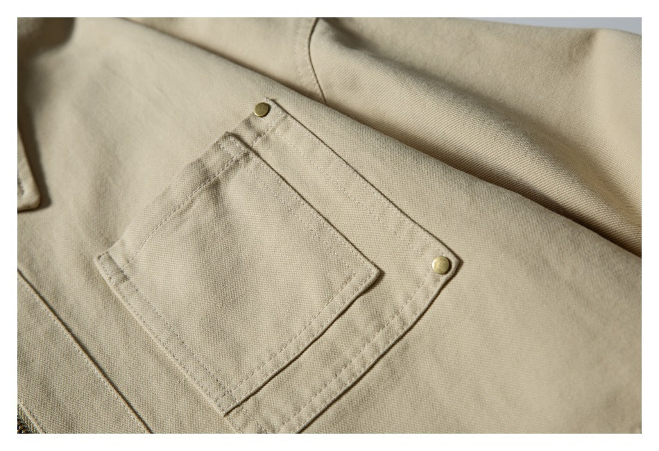 Close-up of a beige jacket pocket with visible stitching and two brass rivets.