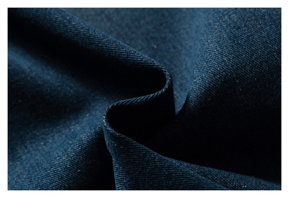 Macro view of dark blue denim fabric draped into soft folds.