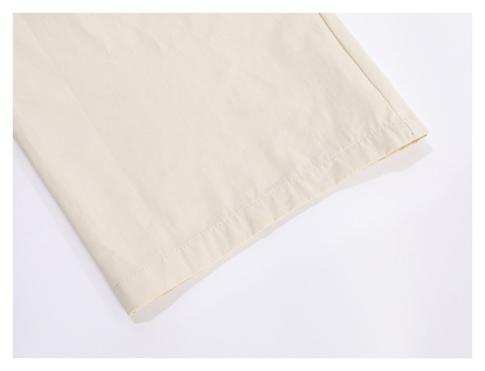 Close-up of the stitched hem on a cream trouser leg.