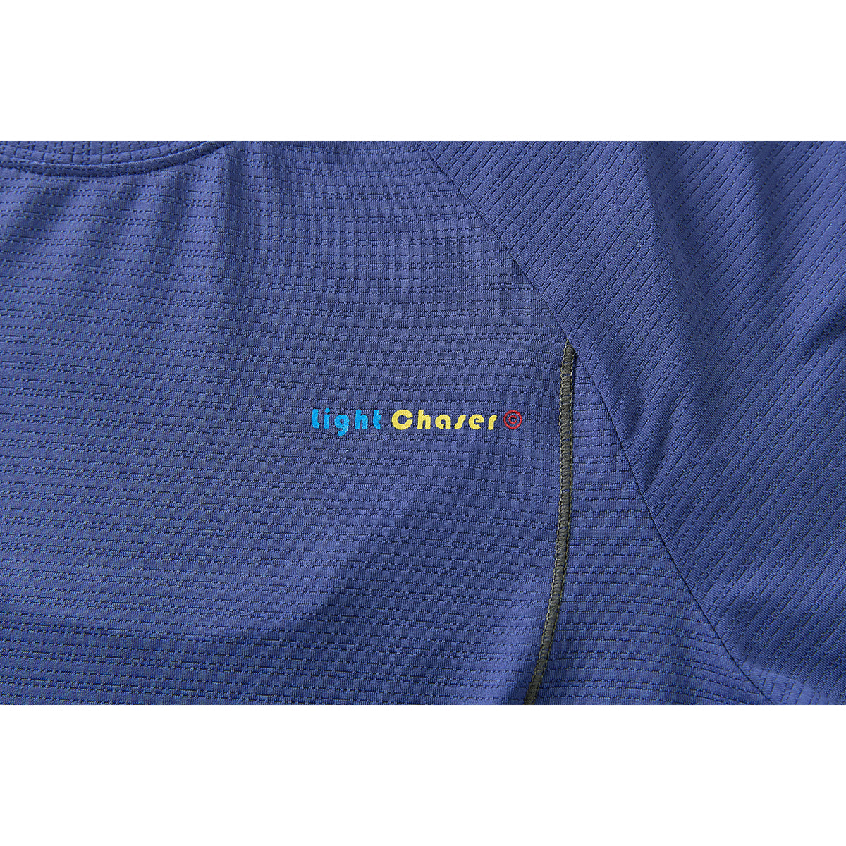 Close-up of a blue shirt showing small multicolored “Light Chaser” text and contrasting seam stitching.
