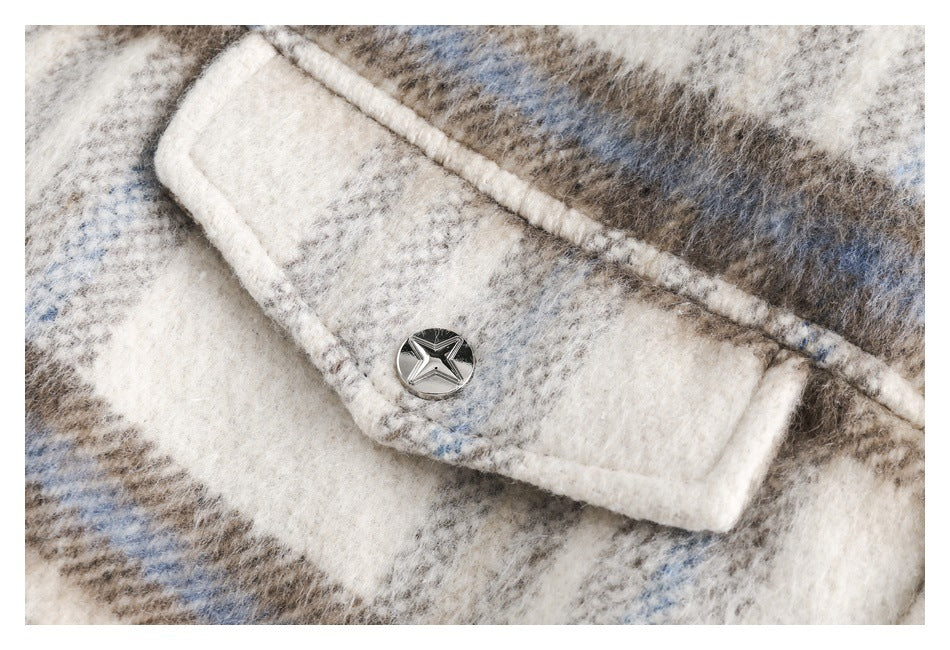 Close-up of a silver star-shaped button on a cream, taupe, and pale blue plaid garment.