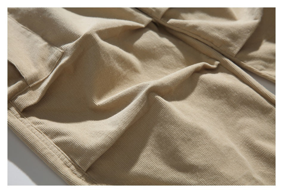 Close-up of beige ribbed trouser fabric and stitched panel seams.