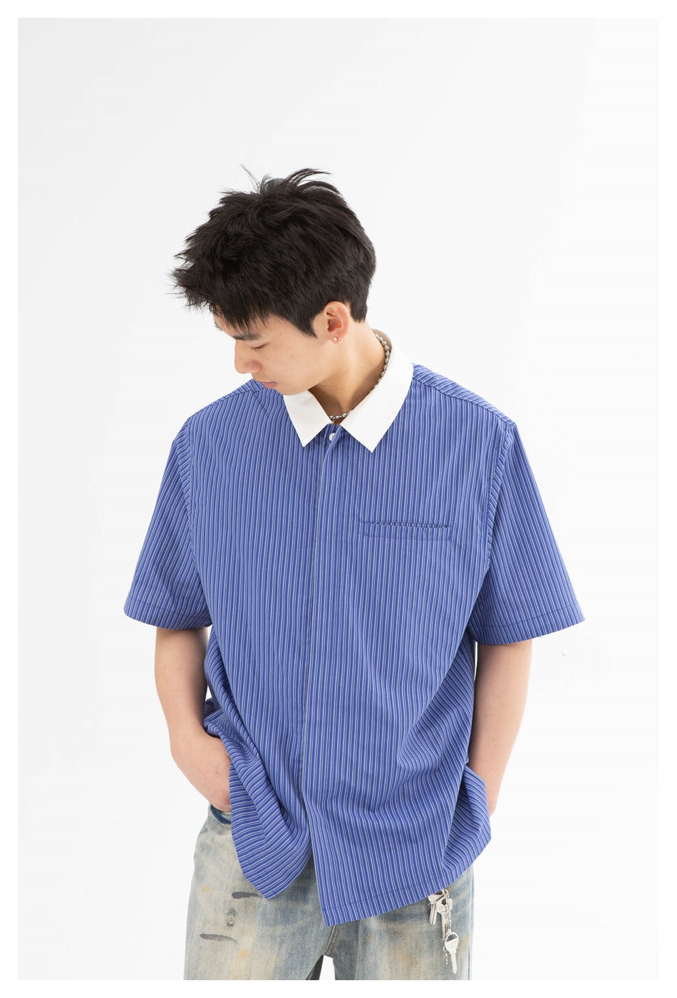 Close view of a model wearing a blue pinstriped shirt with a white collar and small chest pocket.