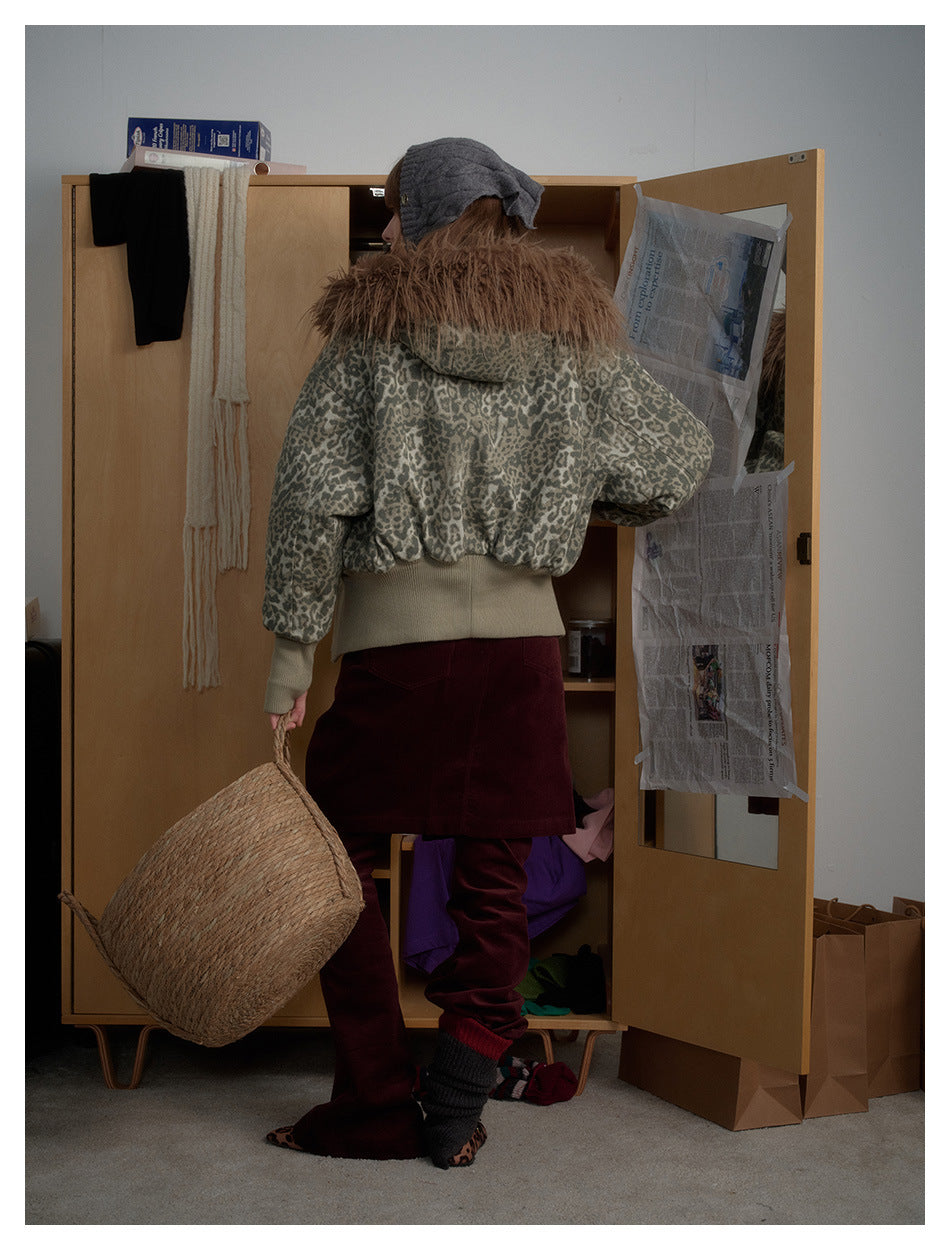 Back view of a model wearing a gray leopard-print jacket with a brown fur-trimmed hood and burgundy trousers.