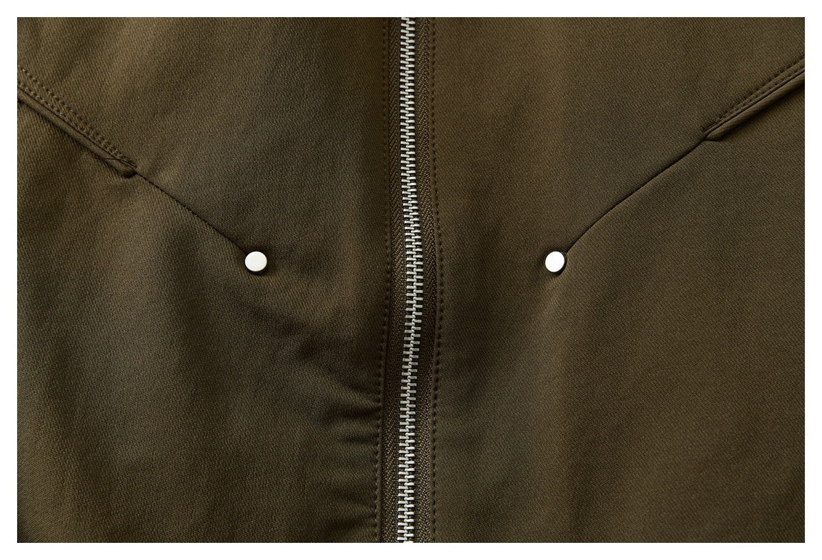 Close-up of the olive-brown jacket's front zipper and two slanted pockets with white snap details.