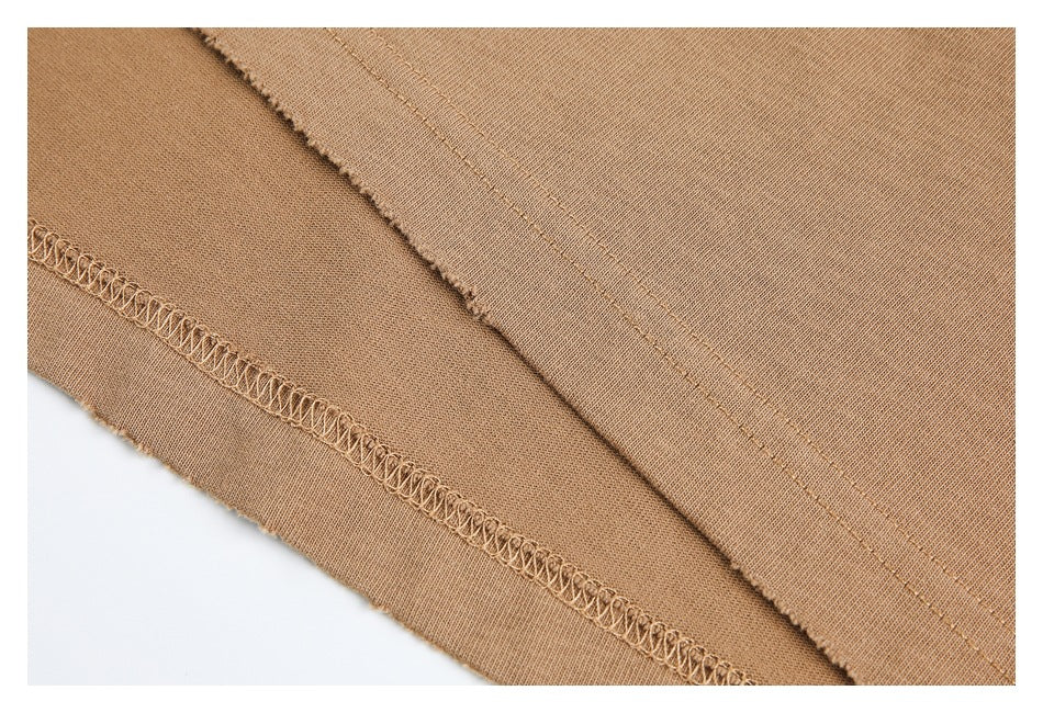 Close-up of tan garment construction, showing an interior overlocked seam and parallel stitching.