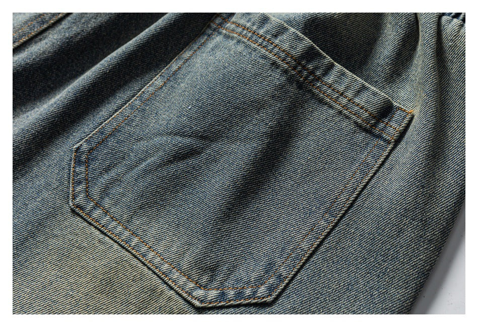 Close-up of a stitched patch pocket on washed blue denim pants.