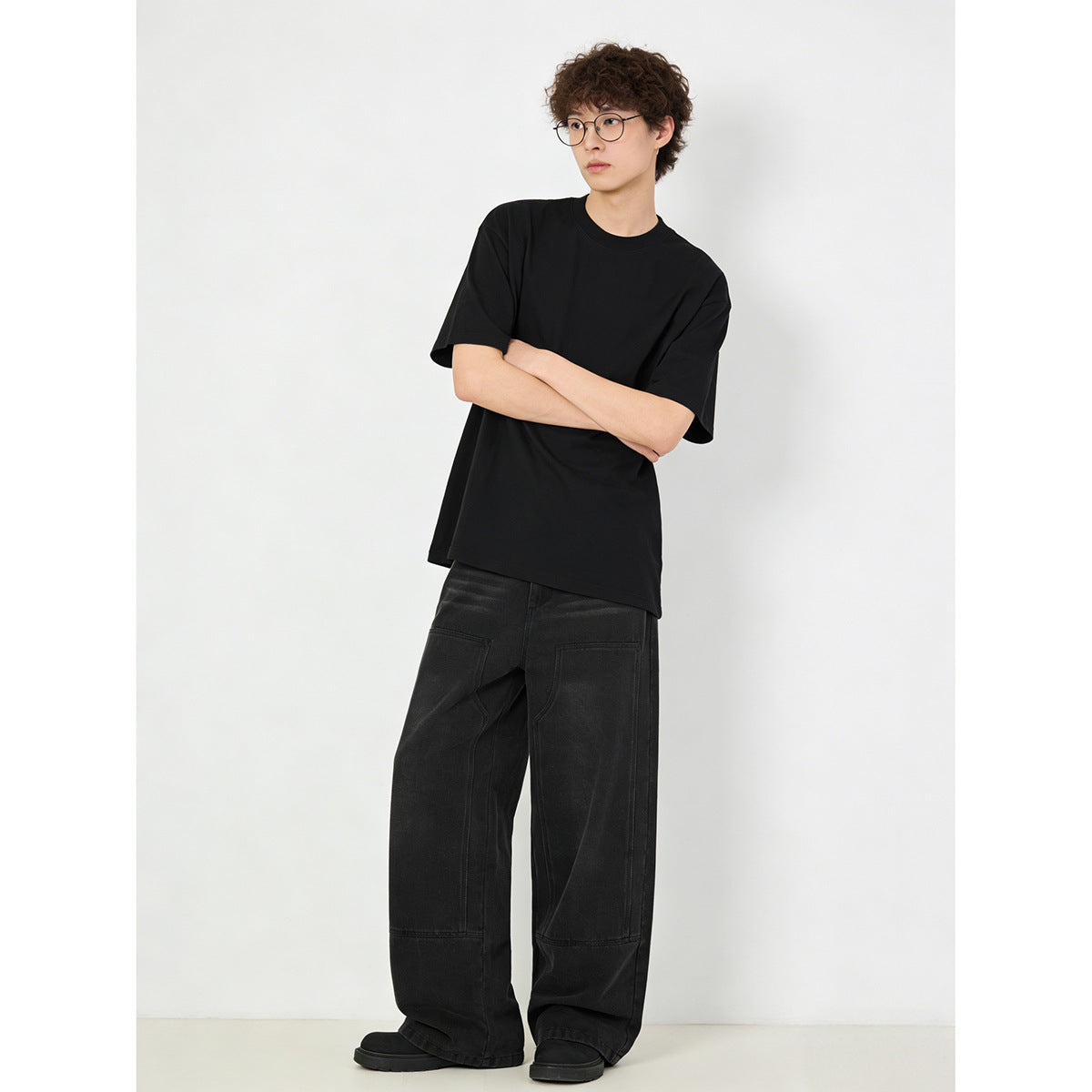 Model wearing a plain black short-sleeve T-shirt and loose black jeans with large panel pockets.