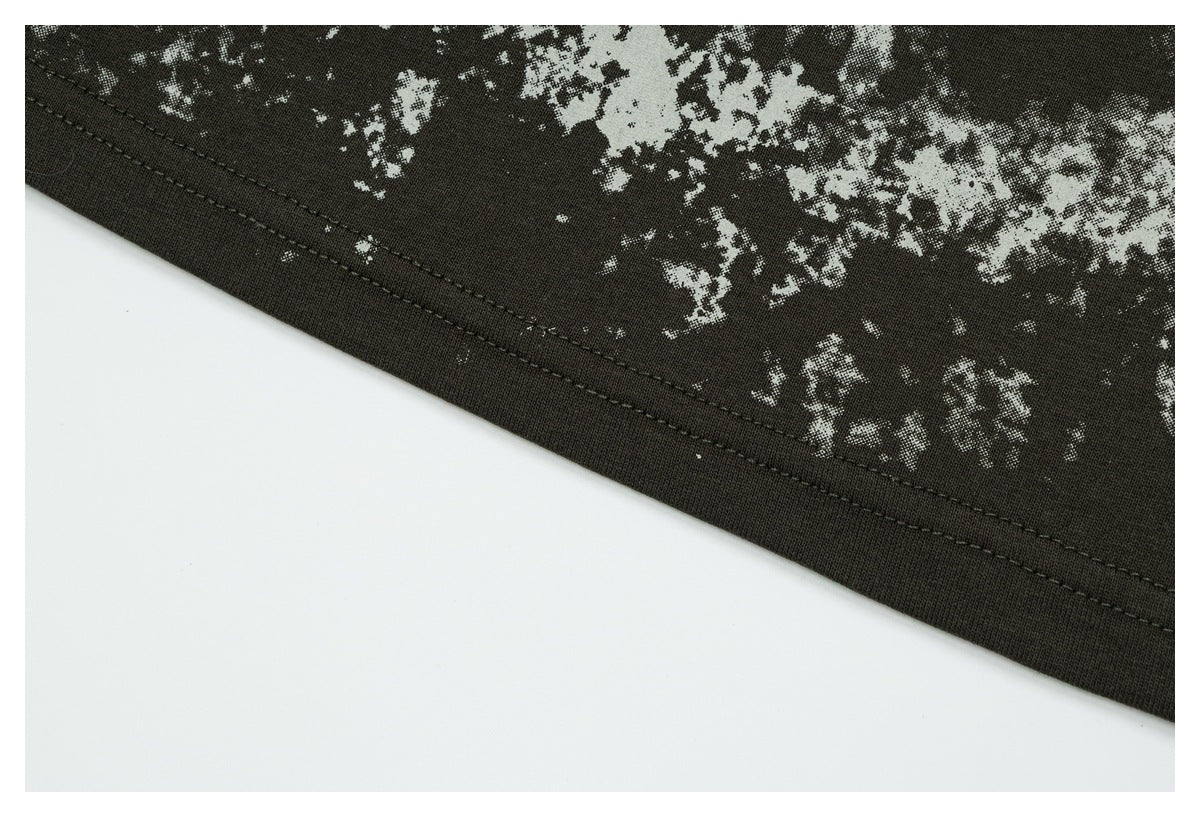Close-up of the shirt's stitched hem beneath a distressed white print on dark olive fabric.
