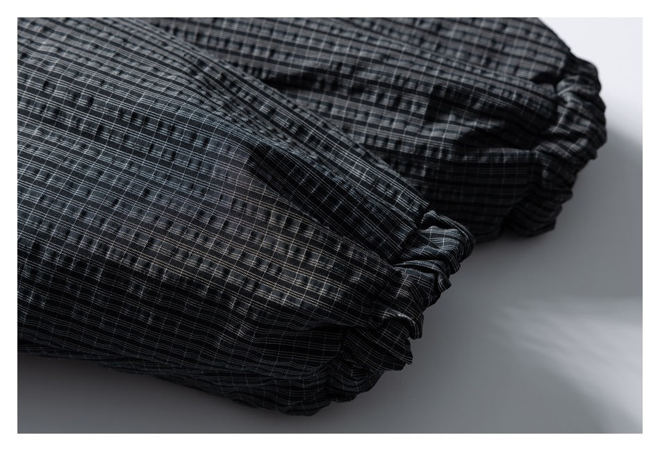 Close-up of a gathered elastic edge on a dark gray plaid garment.