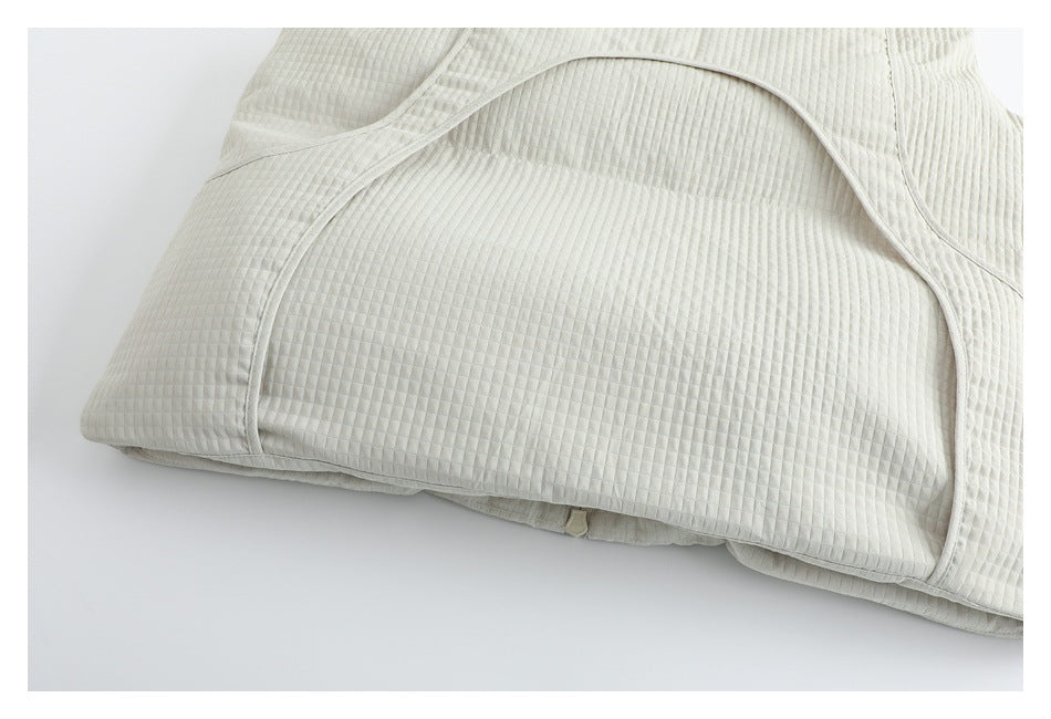 Close-up of ivory quilted fabric and curved stitched paneling near the hem.