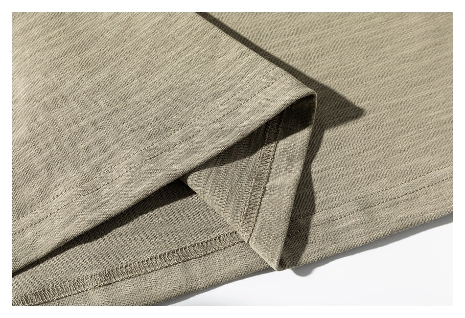 Close-up of the khaki shirt's folded hem, showing double stitching and the interior seam finish.