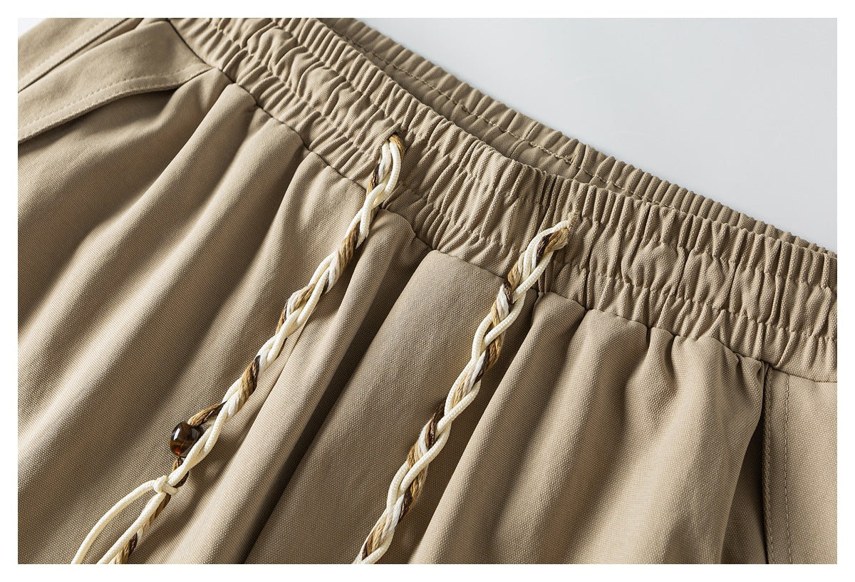 Close-up of khaki shorts with a gathered elastic waistband and cream-and-brown braided drawstrings.
