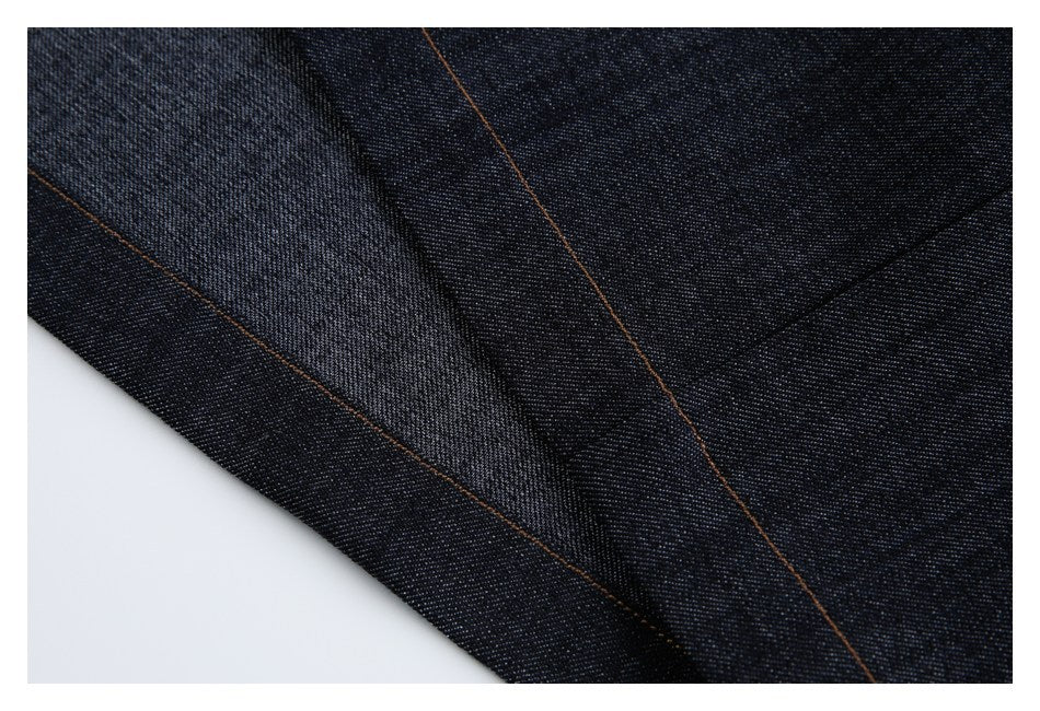 Close-up of dark indigo denim fabric with overlapping panels and brown topstitching.