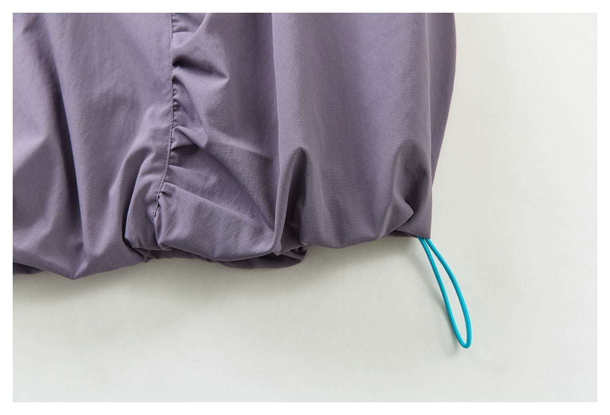 Close-up of a turquoise loop cord emerging from the hem of the muted purple skirt.