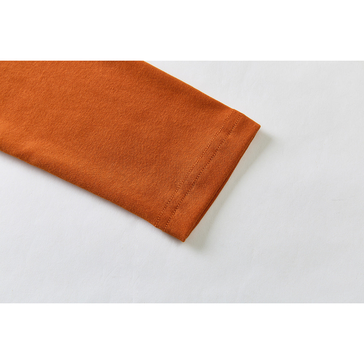 Close-up of the rust-orange sleeve and its stitched cuff hem.