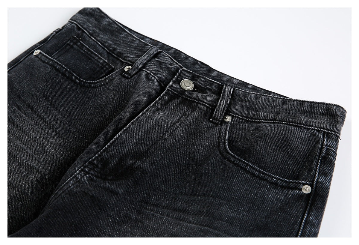 Close-up of black jeans showing the waistband, button, belt loops, zipper fly and front pockets.