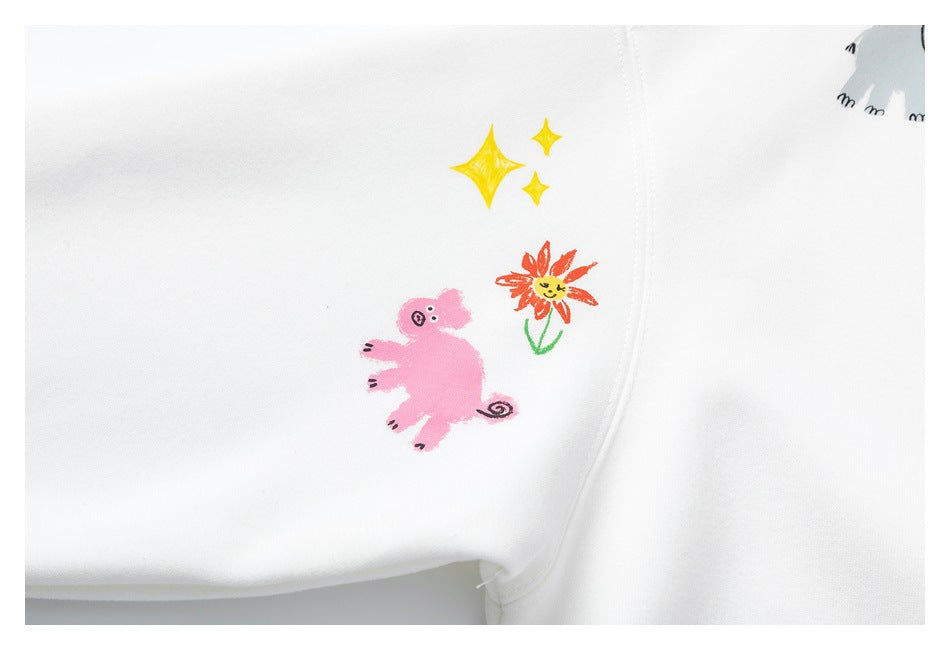 Close-up of a white sweatshirt sleeve printed with a pink creature, a flower, and yellow stars.