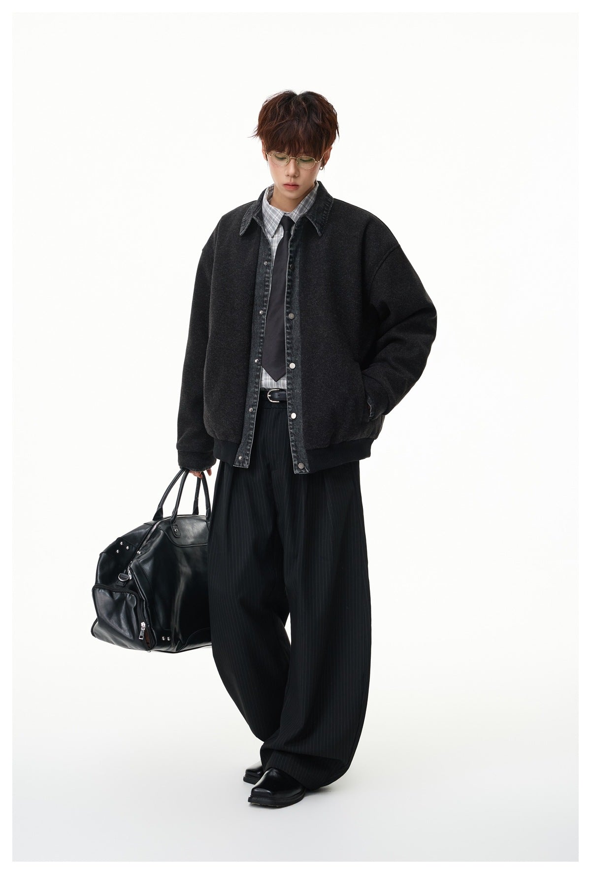 Full-length model wearing a charcoal jacket with a denim collar and snap front, paired with pinstripe trousers.
