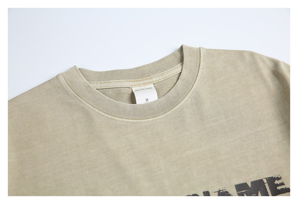 Close-up of the ribbed crew neck and upper chest of a plain sand-beige T-shirt.
