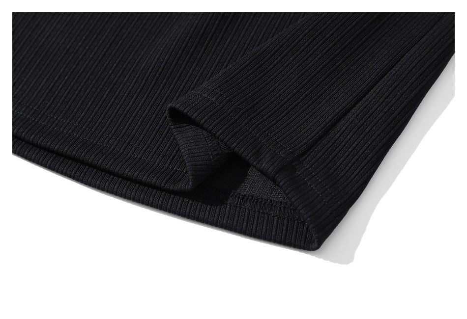 Close-up of a black ribbed garment hem with a small side slit.