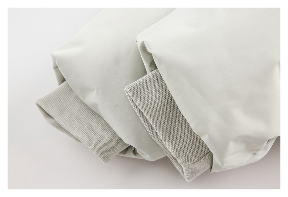 Close-up of white jacket sleeves with wide ribbed knit cuffs.