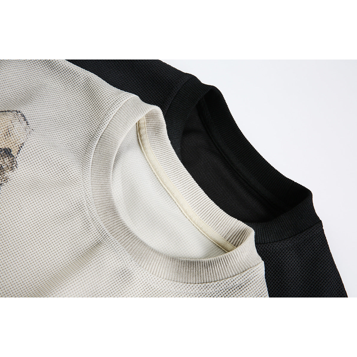 Close-up of cream and black long-sleeve tops showing their ribbed crew necklines and textured knit.