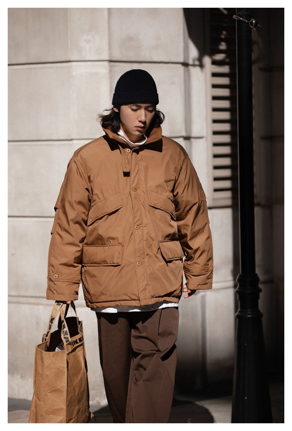 Front view of a model wearing the brown hooded jacket with multiple flap pockets and a button-front closure.