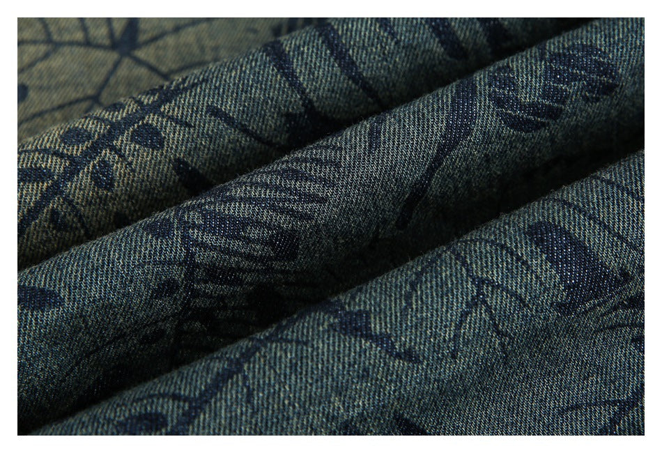 Close-up of draped blue-gray garment fabric with a dark abstract leaf and line print.